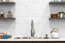 Thumbnail for Modern kitchen with stainless steel sink, sleek faucet, marble backsplash, floating shelves, and white kettle.
