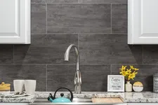 Thumbnail for Modern kitchen sink with stainless steel faucet, turquoise kettle, grey tile backsplash, and yellow flowers.