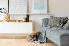 Thumbnail for Modern living room with gray sofa, patterned cushions, wicker baskets, wooden cabinet, and minimalist wall art.