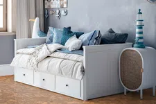 Thumbnail for Cozy nautical-themed bedroom with white daybed, blue cushions, marine decor, and cork flooring under natural light.