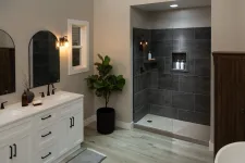 Thumbnail for Modern bathroom with white double vanity, black fixtures, indoor plant, and walk-in shower with dark tiles and glass door