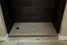 Thumbnail for Modern walk-in shower with dark wall tiles and light gray stone shower base with drain