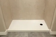 Thumbnail for Empty white rectangular shower base with beige tiled walls and gray floor tile in a bathroom.