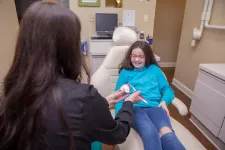 Thumbnail for Dentist demonstrating proper tooth brushing technique to smiling girl sitting in dental chair at clinic.