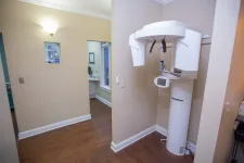 Thumbnail for Dental panoramic X-ray machine in a clean, modern dental office with wood flooring and beige walls.