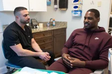 Thumbnail for Dentist in black scrubs consulting a male patient in a burgundy Nike hoodie in a modern dental office.