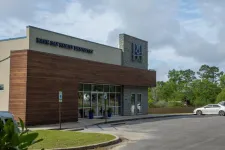 Thumbnail for Modern Back Bay Family Dentistry building with wood and stone exterior and adjacent parking lot under a cloudy sky