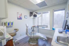 Thumbnail for Bright dental clinic room with modern chair, equipment, large window, and clean wooden floor.