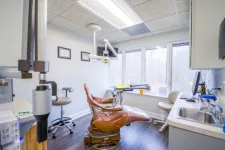 Thumbnail for Modern dental clinic room with brown dental chair, equipment, large window, and clean white walls.
