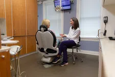 Thumbnail for Dentist consulting with female patient in a modern dental office with equipment and screens visible.