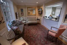 Thumbnail for Cozy waiting room with cushioned chairs, patterned rug, a reception desk, and warm lighting in a professional setting
