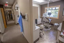 Thumbnail for Modern dental clinic hallway leading to a treatment room with dental chair, equipment, and window with blinds.