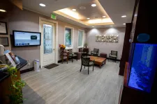 Thumbnail for Modern waiting room with chairs, wooden table, wall art, aquarium, and television screen near entrance door.