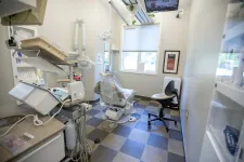 Thumbnail for Bright dental office with patient chair, dental equipment, and a TV mounted near the window on checkered floor.