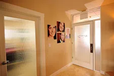 Thumbnail for Bright hallway with frosted glass doors and portrait photos on beige walls in a professional office setting