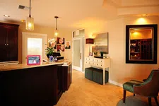 Thumbnail for Warmly lit dental office reception area with dark wood desk, modern pendant lights, and comfortable seating.