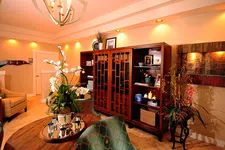 Thumbnail for Cozy living room with wooden cabinets, round table with flowers, upholstered chairs, and warm ambient lighting