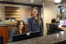 Thumbnail for Two female medical staff smiling and working together at a computer in a clinic reception area