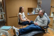 Thumbnail for Dentist and male patient having a conversation in a dental office with equipment visible around.