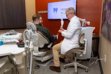 Thumbnail for Dentist in white coat consulting smiling male patient sitting in dental chair in modern clinic room.