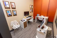 Thumbnail for Modern dental office consultation room with contemporary chairs, computer station, and award plaques on wall.