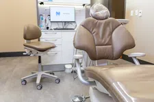 Thumbnail for Modern dental clinic room with brown dental chair, dentist stool, and monitor displaying a tooth logo.