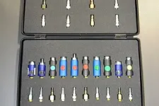 Thumbnail for Open black carrying case with organized rows of blue and black connectors and small metal adapters.