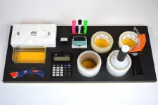 Thumbnail for Office supplies including tissue box, markers, tape dispensers, calculator, and cutter arranged on black surface.