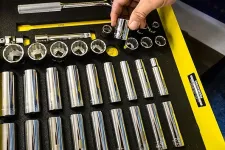 Thumbnail for Person selecting a chrome socket from an organized tool tray with various socket sizes and wrench handles.