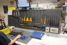 Thumbnail for Man working at a workshop desk with organized tools hanging on a pegboard and a computer monitor above.