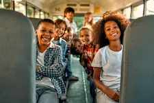 Thumbnail for Happy diverse children smiling together on a school bus, showcasing friendship and joy.