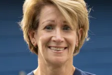 Thumbnail for Smiling woman with short blonde hair wearing a navy blue Tech Support t-shirt against a blue background