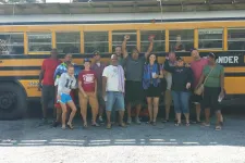 Thumbnail for a group of people standing in front of a school bus
