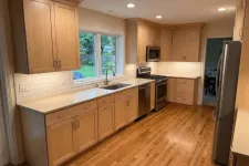 Thumbnail for Bright modern kitchen with wooden cabinets, stainless steel appliances, white countertops, and hardwood floors.
