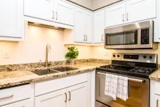 Thumbnail for Modern kitchen with white cabinets, granite countertops, stainless steel stove and microwave, double sink.