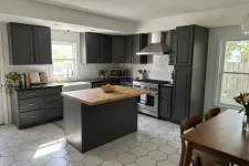 Thumbnail for Modern kitchen with dark cabinets, wooden island countertop, stainless steel appliances, and hexagonal floor tiles