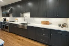 Thumbnail for Modern kitchen with dark wood cabinets, white marble countertops, farmhouse sink, and stainless steel appliances.