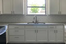 Thumbnail for Modern kitchen with white cabinets, granite countertops, subway tile backsplash, stainless steel appliances, and a window above the sink