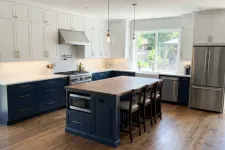 Thumbnail for Modern kitchen with navy lower cabinets, white upper cabinets, wood island, stainless steel appliances, and hardwood floors.