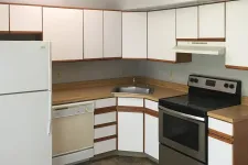 Thumbnail for Compact kitchen with white cabinets, wood countertops, stainless steel stove, white refrigerator, and tiled floor.