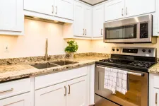 Thumbnail for Modern kitchen with white cabinets, granite countertops, double sink, stainless steel oven, and microwave.