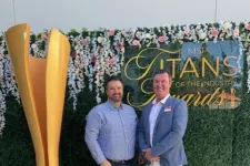 Thumbnail for Two men posing beside a large golden award trophy at the MSP Titans of the Industry Awards event with floral backdrop.