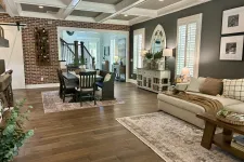Thumbnail for Open living and dining area with wood floors, brick accent wall, neutral furniture, and decorative accents.
