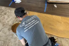 Thumbnail for Professional flooring installer spreading adhesive on subfloor preparing for hardwood installation.