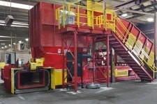 Thumbnail for Large industrial metal shredder machine in a factory with red and yellow safety railings and stairs