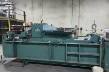 Thumbnail for Industrial green machine with rotating mechanism in a warehouse with shelves and equipment.