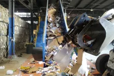 Thumbnail for Recycling facility conveyor belt loaded with cardboard and paper waste being handled by industrial machinery.