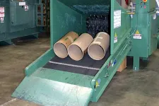 Thumbnail for Industrial paper tube shredding machine processing large cardboard tubes on a factory floor conveyor belt.