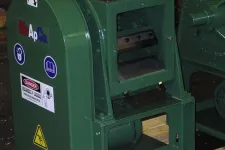 Thumbnail for Green industrial machine with warning labels and safety signs in a workshop setting.