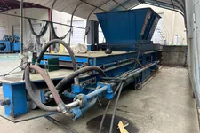Thumbnail for Large industrial blue metal machine with hoses inside a covered workspace on concrete floor.